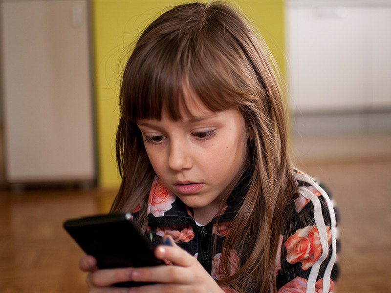 Маленькая девочка-гаджетоманка со смартфоном в руках